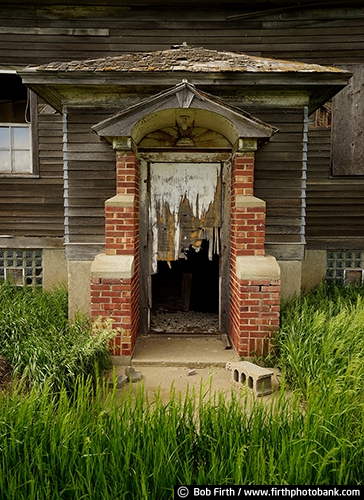 South Dakota;Black Hills;SD;old schoolhouse;old school;old building;exterior view;summer;tall grass;broken door;falling apart;moldering;ruins;falling down;old door;abandoned places;deserted