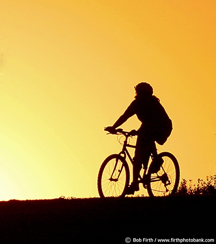 bicycling;cycling;cyclist;exercise;fun pastime;Minnesota;MN;peaceful;recreation;relaxing;silhouette;solitude;summer;sunset;woman;golden sky;mountain bike