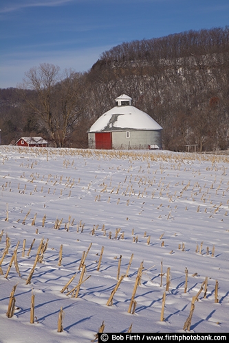 round barn;Wisconsin;winter;trees;snow covered farm fields;silver barn;hills;grey barn;farm buildings;farm scene;Dell Wisconsin;country;corn stubble;backroads;agriculture;agricultural scene;rural